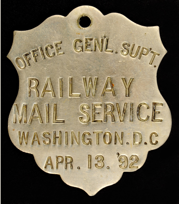 Metallabzeichen mit "Railway Mail Service Washington, D.C." Text auf schwarzem Hintergrund.
