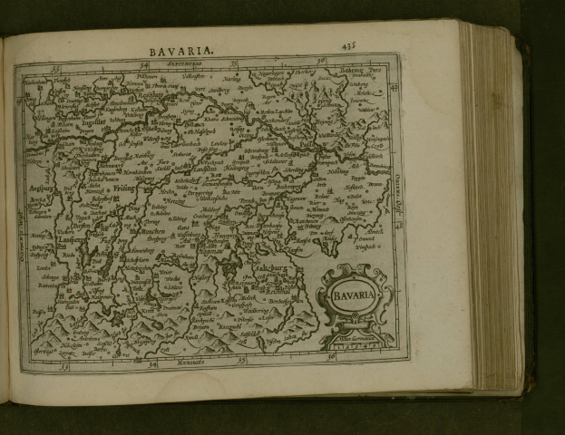 Ein aufgeschlagenes Buch, das eine detaillierte Karte von Bayern zeigt, mit beschrifteten Städten und Ortschaften, begleitet von erklärendem Text.