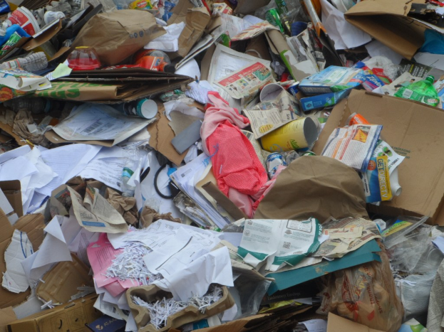 Ein Stapel Kartonboxen mit verschiedenen Gegenständen wie Papieren, Flaschen und Deckeln.