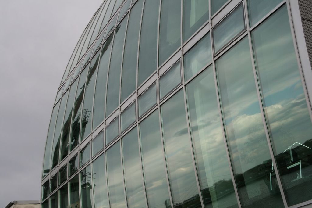 Ein großes Glas-Korporationsgebäude mit einem blauen Himmel im Hintergrund.