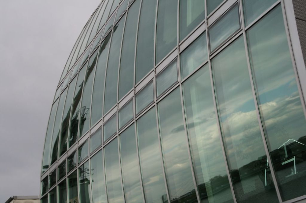 Ein großes Glas-Korporationsgebäude mit einem blauen Himmel im Hintergrund.