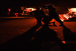 Zwei Männer stehen auf einer Bühne bei Nacht, beleuchtet von Hintergrundlichtern, mit Schuhen, als wollten sie performen.