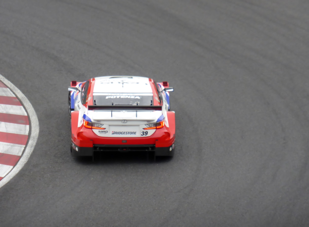 Rotes und weißes Toyota Supra GT3-Sportwagen auf einer Rennstrecke, mit dem Text "Toyota Supra GT3" auf der Seite des Wagens.