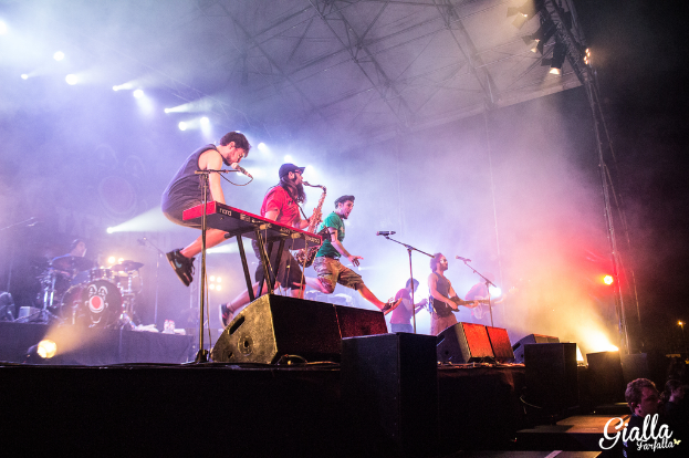 Personen mit Musikinstrumenten und Mikrofonen vor sich.